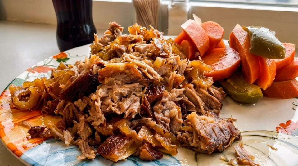 Shredded pork with caramelized onions, pickled carrots, and jalapeños on a decorative plate.
